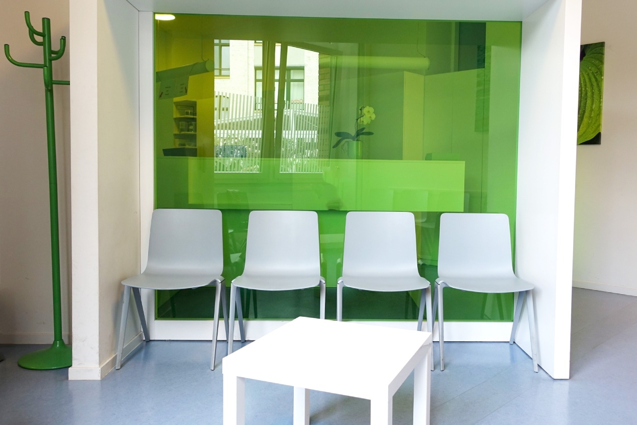 Wartezimmer mit auffälligen, grünen Trennwand im Hintergrund.