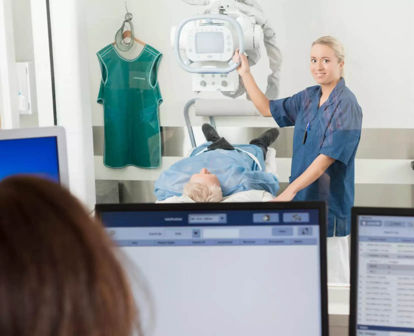 Medizinische Fachangestellte stellt Röntgengerät auf Patient ein