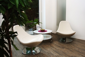 Wartebereich in einer Praxis. Zwei Stühle mit einem Beistelltisch.