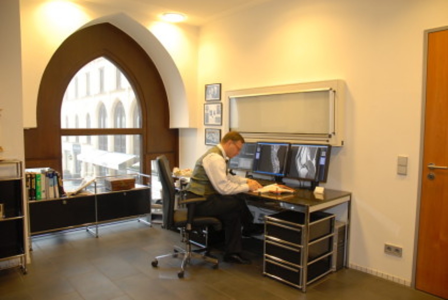 Person sitzt am Schreibtisch im Besprechungsraum.