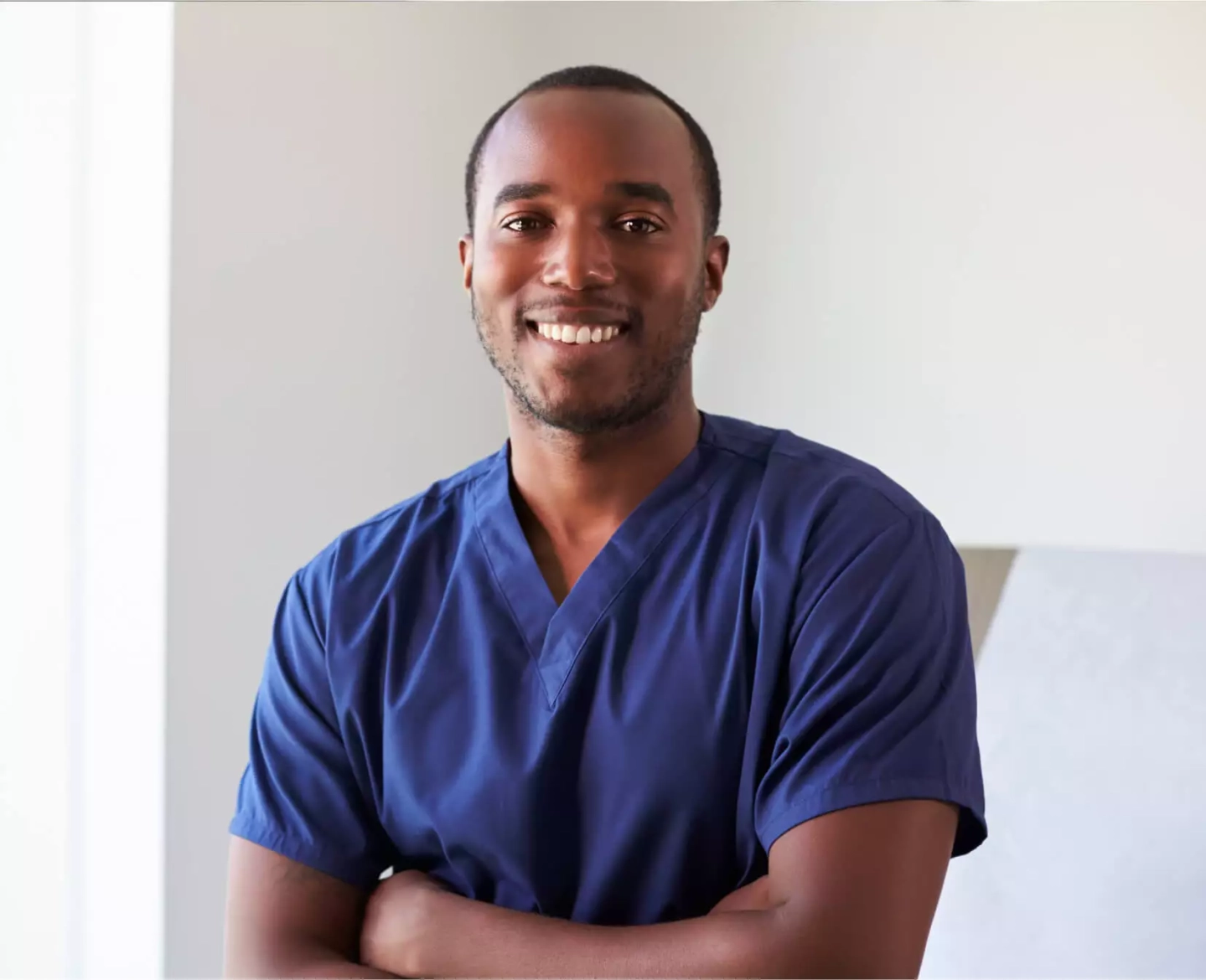 Medizinischer Fachangesteller in blauem Shirt lächelt in die Kamera