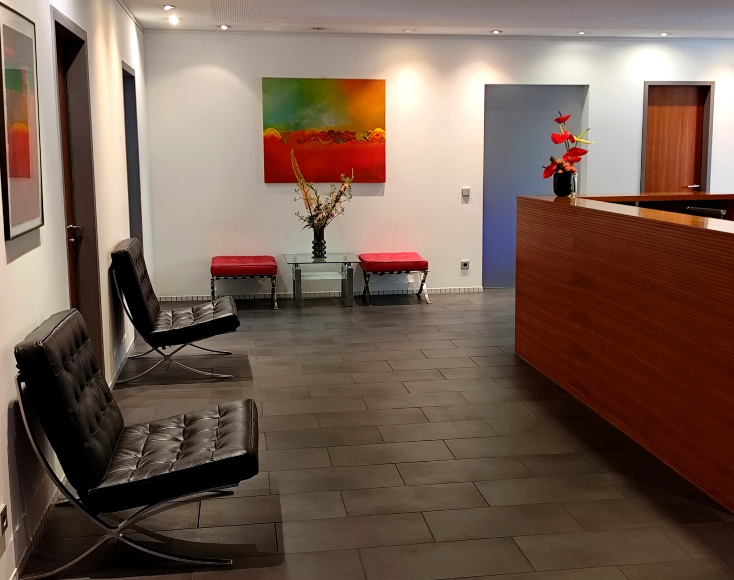 Moderner Empfangsbereich mit Holztresen auf der rechten Seite und bequemen Stühlen.