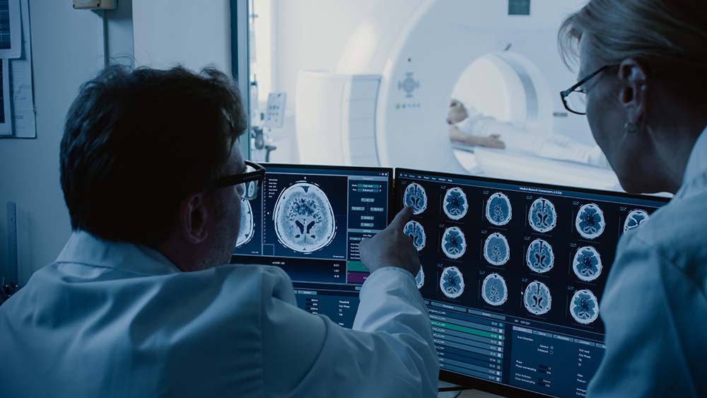 Zwei Ärzte begutachten eine CT-Aufnahme auf zwei Monitoren.