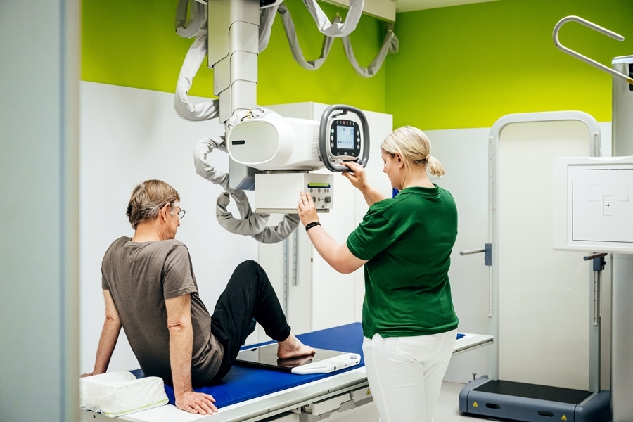 Mitarbeitenden in der Radiologie untersucht einen Patienten mit einem Röntgengerät.