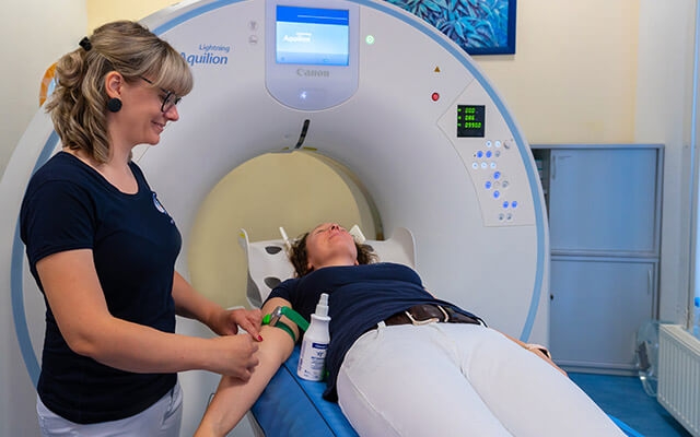 Mitarbeitende bereitet Patientin für eine Untersuchung im CT vor.
