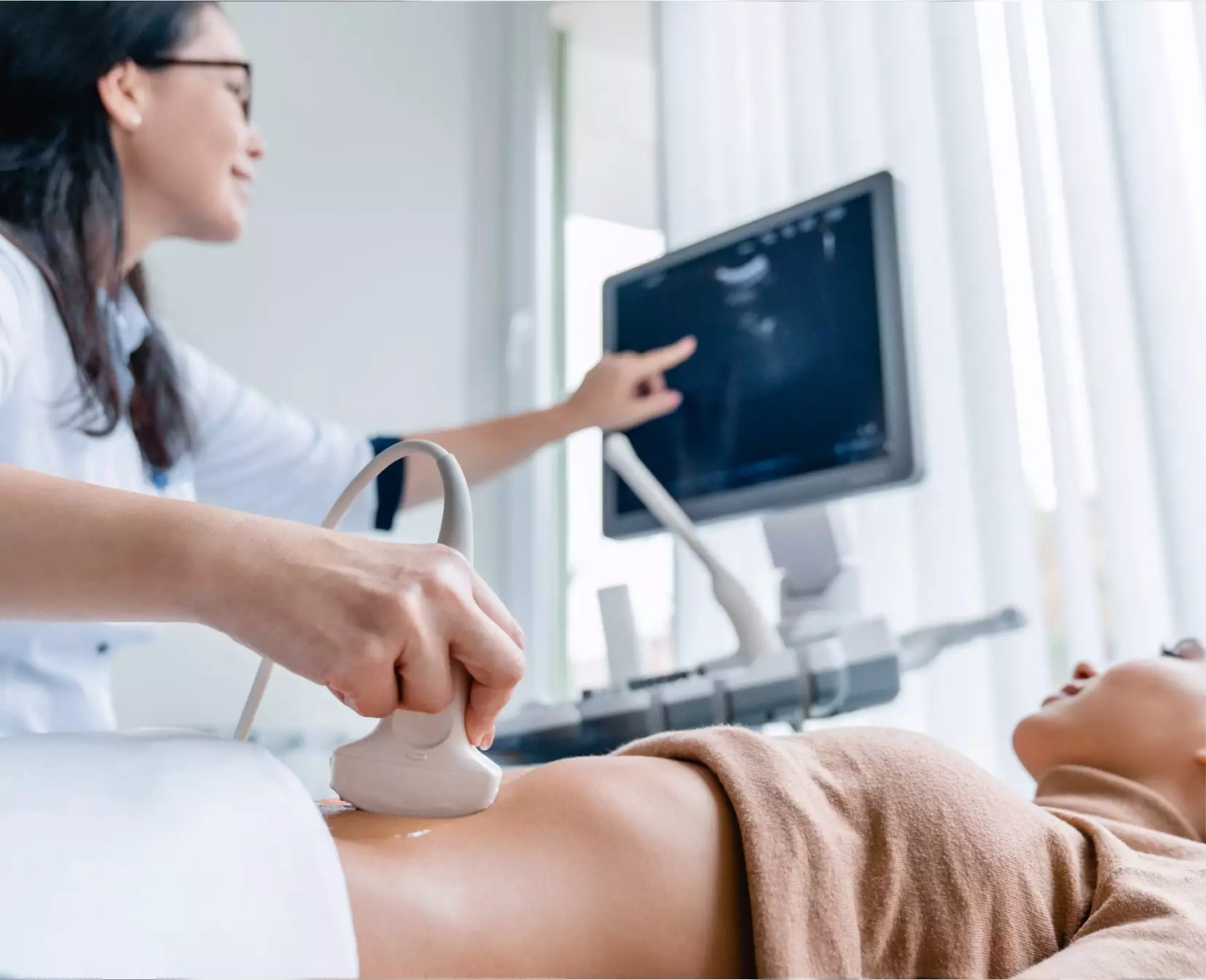 Ärztin untersucht Frau mithilfe von Ultraschallgerät
