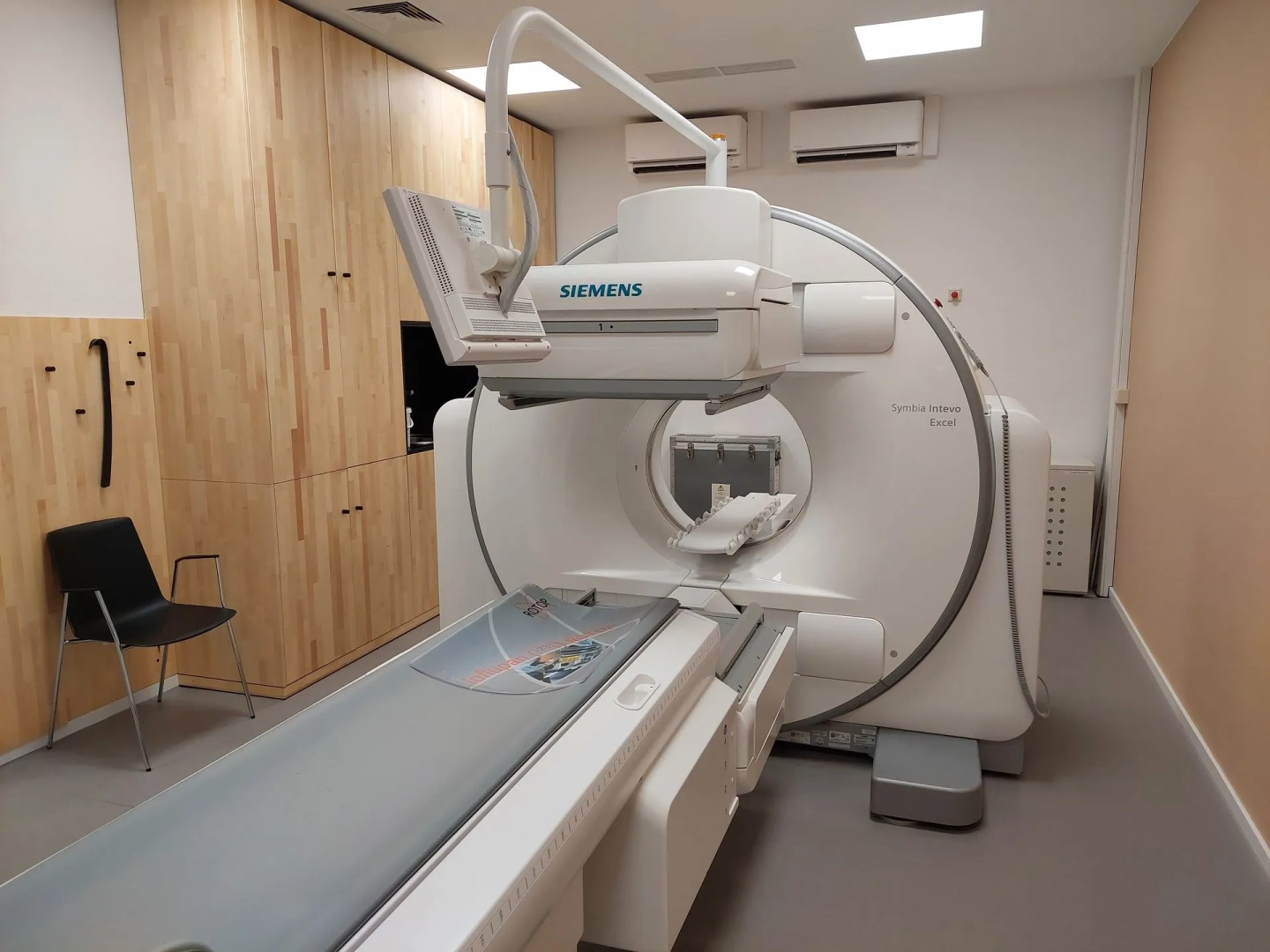 Ein CT-Gerät in einem kompakten Raum mit Holzschränken und einem Stuhl.